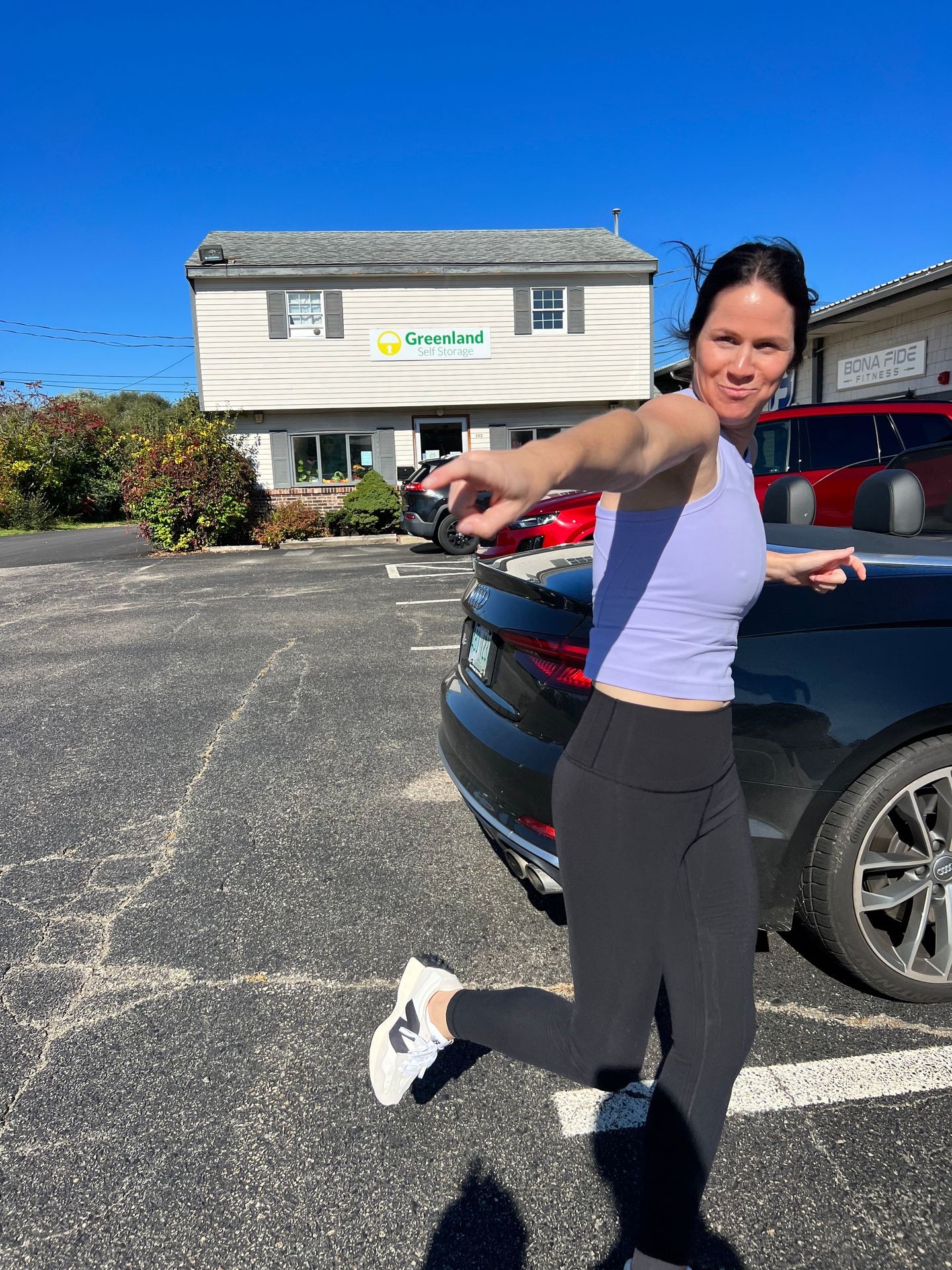 Person wearing athletic clothing jogging in a parking lot with Greenland Self Storage building in the background.